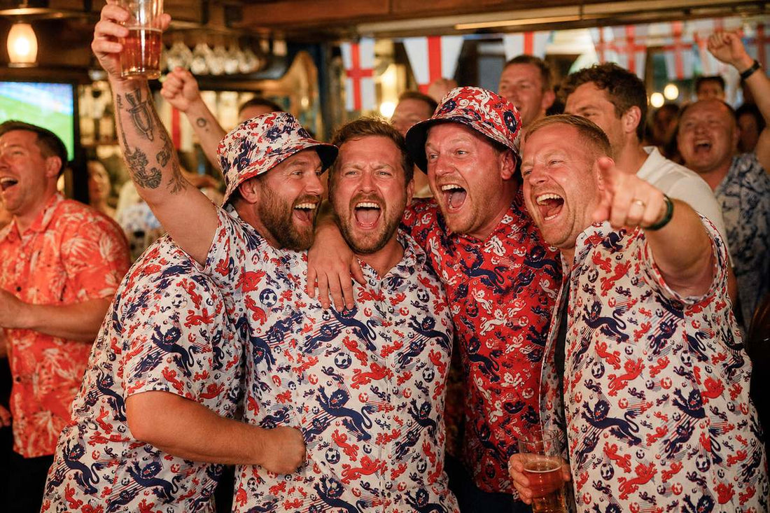 England fans in lion-print Hawaiian shirts and bucket hats cheering with pints in a busy pub
