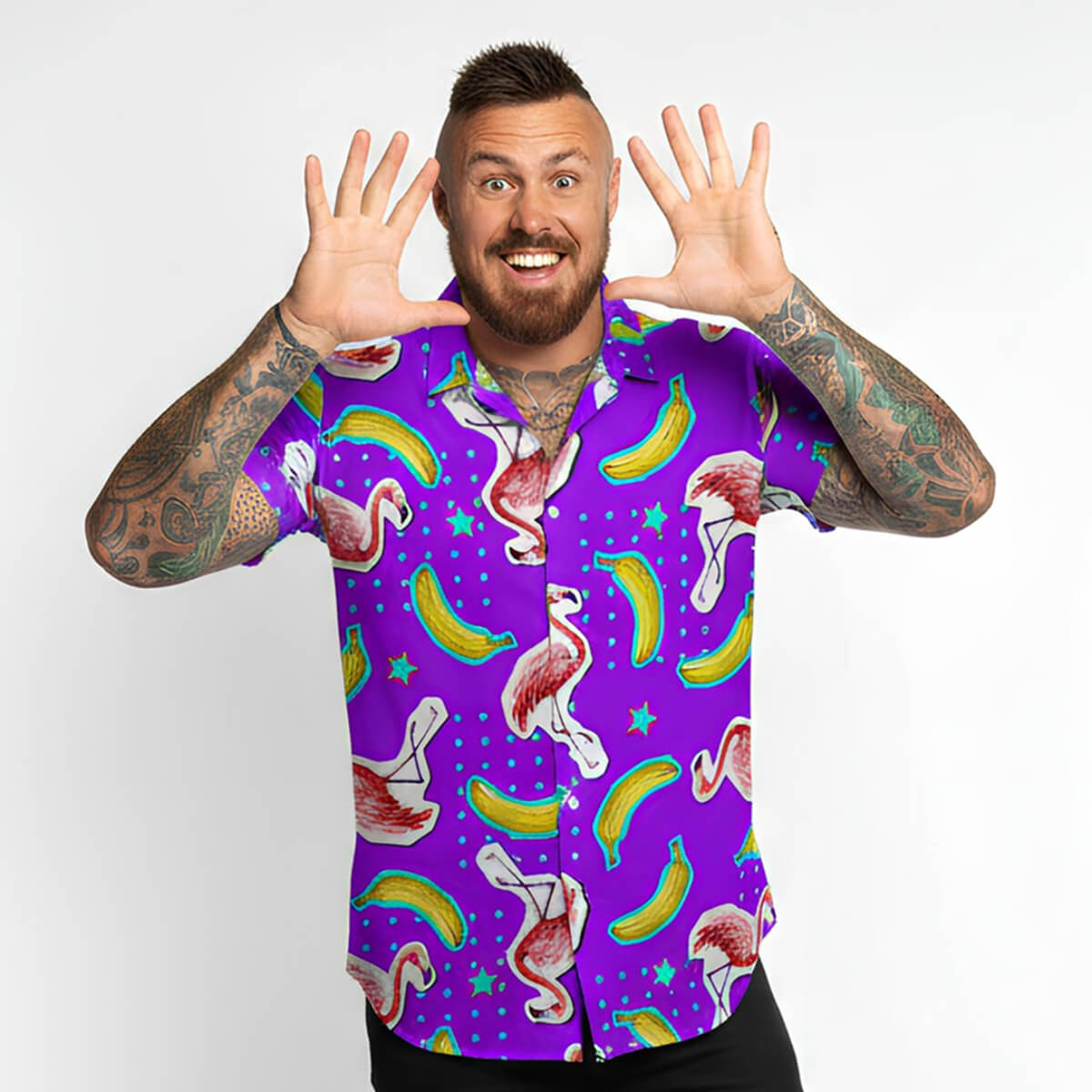 Man wearing a colourful shirt with flamingo and banana pattern on a white background