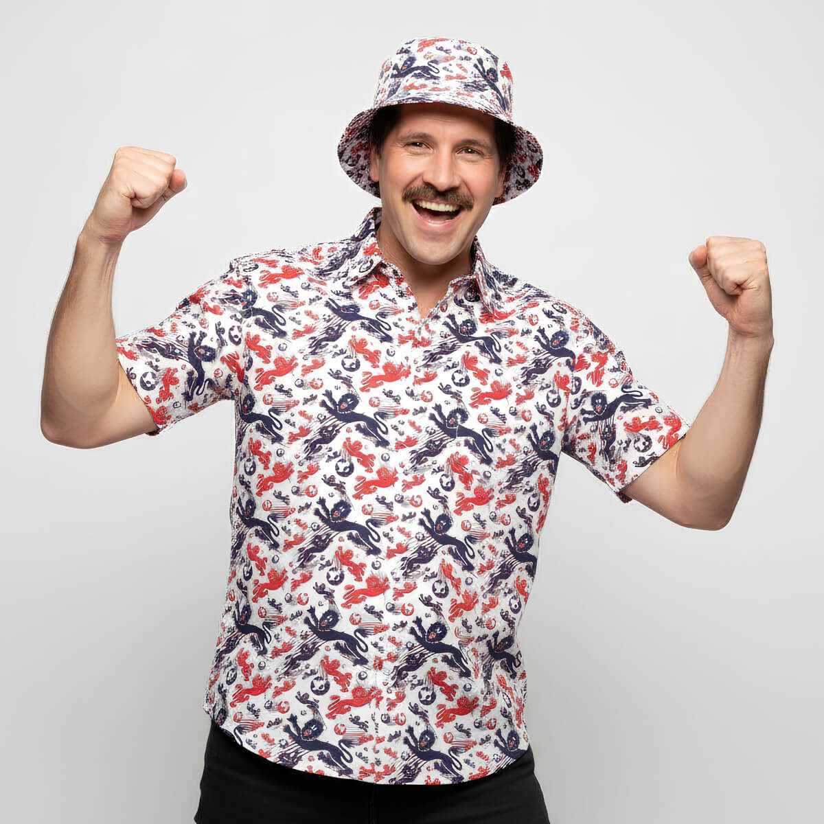 Man wearing a patterned England shirt and bucket hat flexing his muscles on a light gray background
