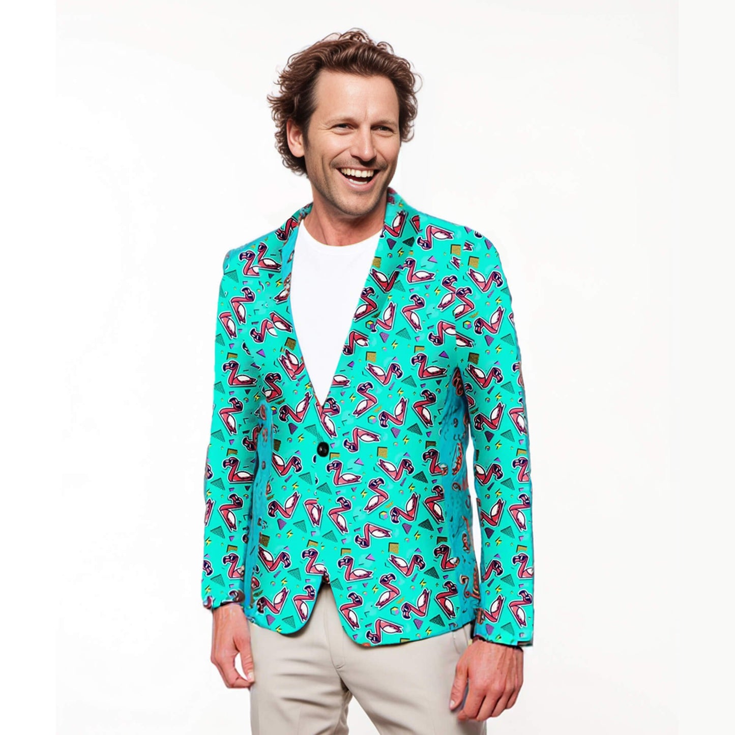 A man smiles in the Flamingo Fandango Blazer, featuring playful pink flamingos and geometric designs, styled over a white tee and beige pants against a plain white background.