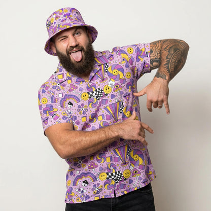 Man wearing a purple patterned shirt and bucket hat, pointing at himself against a white background