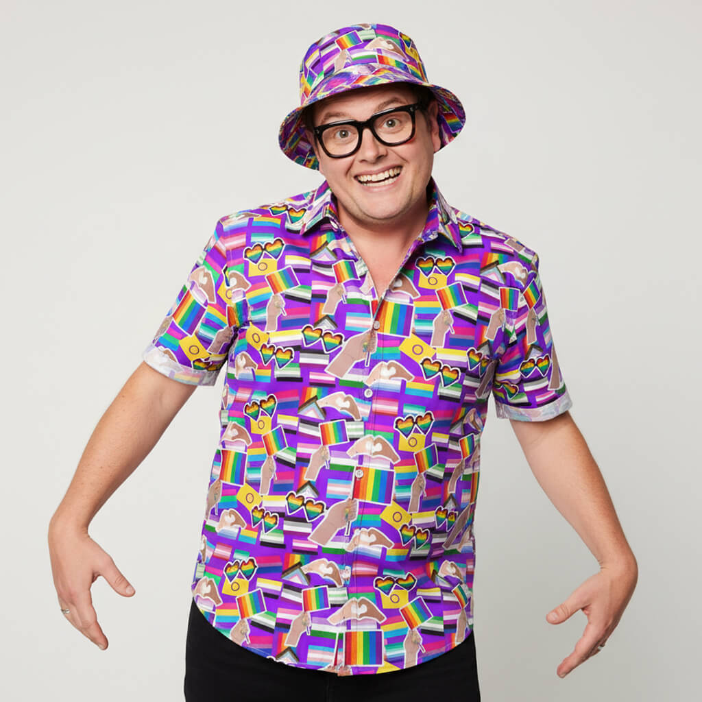 Person wearing a colourful patterned pride shirt and bucket hat on a plain background