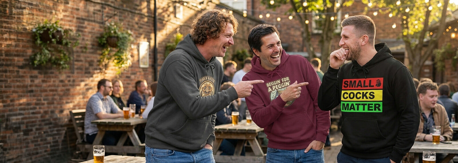 Three men wearing funny hoodies laughing together in a beer garden.
