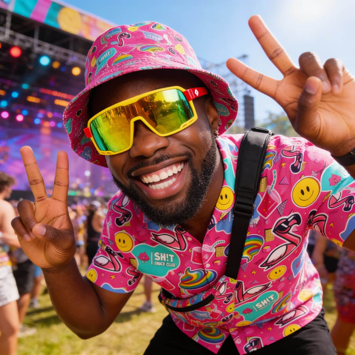 A person at a music festival wearing a colourful shit shirt and sunglasses, making peace signs.