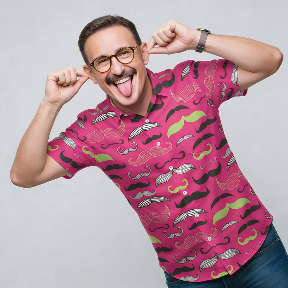 Man wearing a pink shirt with mustache pattern, posing against a gray background