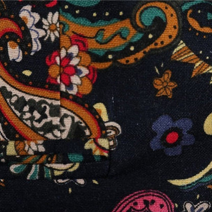 Close-up of the Navy Floral Blazers dark fabric, featuring a bold paisley and floral pattern in yellow, red, blue, orange, and pink. The vibrant textile shows a visible seam and folded corner for added detail.