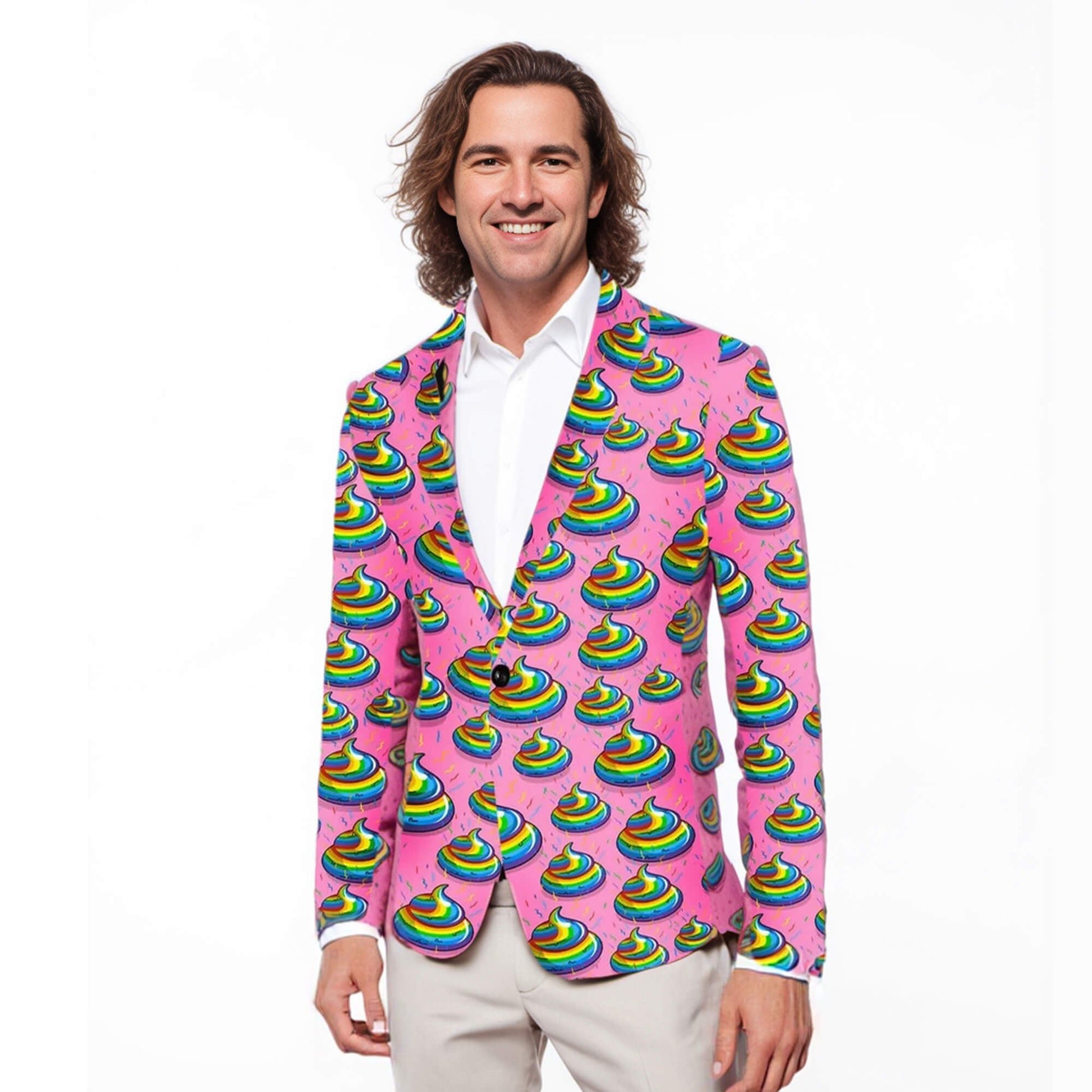 A smiling man stands against a white background, wearing the Unicorn Poo Blazer—a bright pink suit jacket covered in rainbow poop emojis—paired with a white shirt and light gray pants.