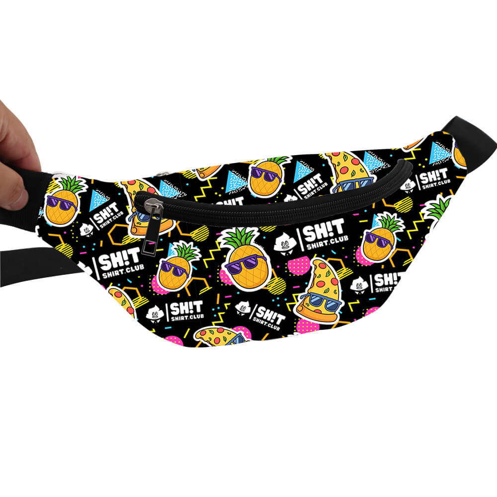 A hand holds the Wanna Pizza This Shirt fanny pack, which has a black background and playful illustrations of pizza slices, pineapples with sunglasses, blue ice cubes, and Bad Shirt Club in white text.